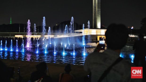 Warga menyaksikan pertunjukan air mancur menari di Taman Lapangan Banteng. Jakarta, Sabtu, 18 Juni 2022. (CNN Indonesia/Adhi Wicaksono)