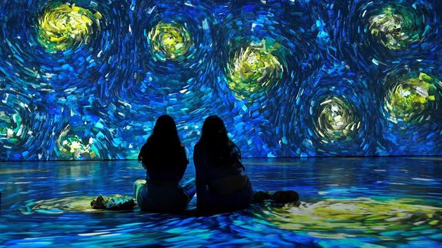 Friends sit on the ground during a Van Gogh 'Immersive Journey' projection, in Dublin, Ireland, June 23, 2022. REUTERS/Clodagh Kilcoyne