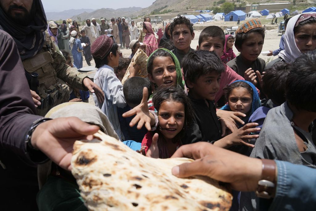 Afghan children line up for bread at a camp after an earthquake in Gayan district in Paktika province, Afghanistan, Sunday, June 26, 2022. A powerful earthquake struck a rugged, mountainous region of eastern Afghanistan early Wednesday, flattening stone and mud-brick homes in the country's deadliest quake in two decades, the state-run news agency reported. (AP Photo/Ebrahim Nooroozi)