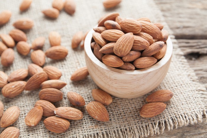 almond group of almonds from wood bowl on wood background