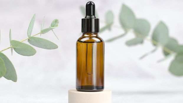 Mock up glass bottle and eucalyptus. A bottle of essential oil or serum on a light background. Natural beauty product. Natural Eucalyptus Oil