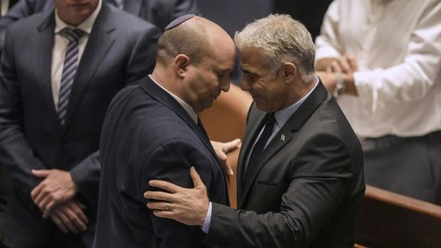 Perdana Menteri Israel Naftali Bennett, kiri, dan Menteri Luar Negeri Yair Lapid bereaksi setelah pemungutan bunyi pada RUU untuk membubarkan parlemen di Knesset, parlemen Israel, di Yerusalem, Kamis, 30 Juni 2022. (AP/Ariel Schalit)