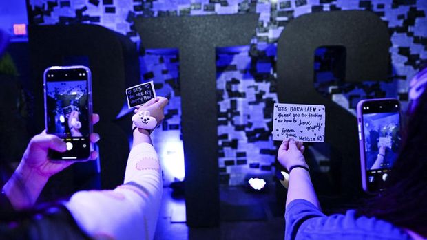 K-pop fans take pictures of their notes written on stickers to post on a wall as they visit a BTS pop-up store to promote the album 'Proof' in Los Angeles, California on June 15, 2022. - K-pop supergroup BTS announced June 14, 2022 they were taking an indefinite break from one of the world's most popular acts to focus on solo (Photo by Patrick T. FALLON / AFP)