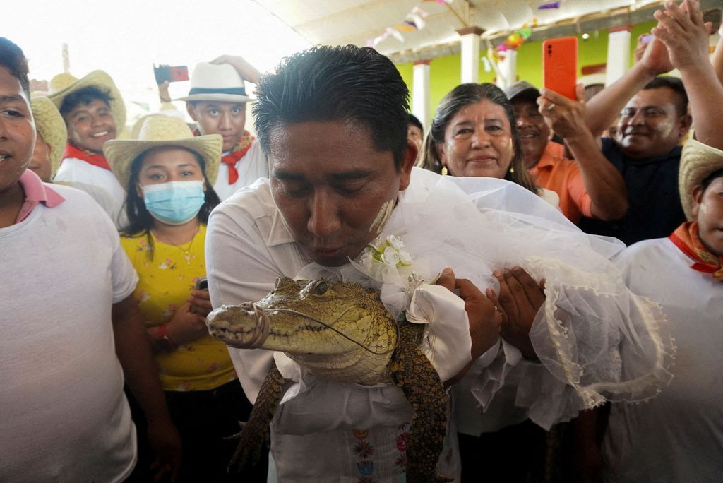 The San Pedro Huamelula Mayor Victor Hugo Sosa kisses a seven-year-old alligator dressed as a bride during a traditional ritual marriage, likely dates back centuries to pre-Hispanic times, between the mayor and the reptile that depicts a princess, as a prayer to plead for nature's bounty, in San Pedro Huamelula, in Oaxaca state, Mexico June 30, 2022. REUTERS/Jose de Jesus Cortes     TPX IMAGES OF THE DAY