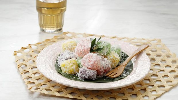 Colorful Ongol Ongol or Sentiling, Steamed Cassava Cake Coating with Grated Coconut, Served on Ceramic Plate. Copy Space for Text