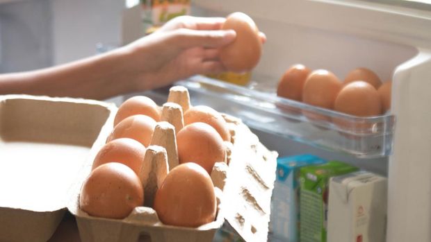 Hand Pick chicken egg from egg carton box into refrigerator, eggs on shelf of cold storage