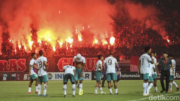 Suporter menyalakan flare di laga Indonesia vs Myanmar dalam Piala AFF U-19 2022 di Stadion Patriot Candrabhaga, Minggu (10/7/2022).