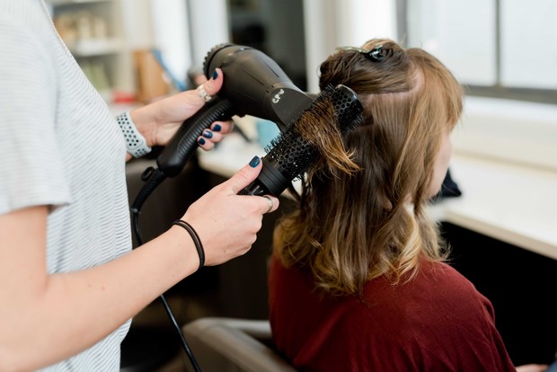 Orang sedang mengeringkan rambut dengan hair dryer
