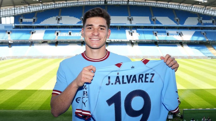 Julian Alvarez MANCHESTER, ENGLAND - JULY 10: Julian Alvarez of Manchester City poses with a Manchester City shirt inside the stadium during the Manchester City Summer Signing Presentation Event at Etihad Stadium on July 10, 2022 in Manchester, England. (Photo by Matt McNulty - Manchester City/Manchester City FC via Getty Images)