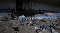 Seorang warga melintas di stadion Bakhmut yang rusak dirudal.