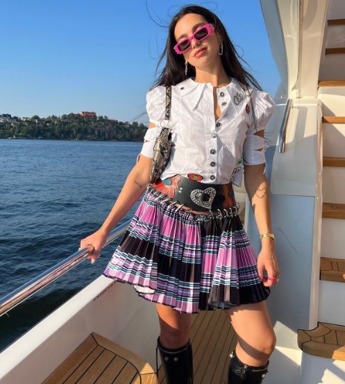 Dua Lipa memadukan kemeja putih dan rok mini motif kotak-kotak