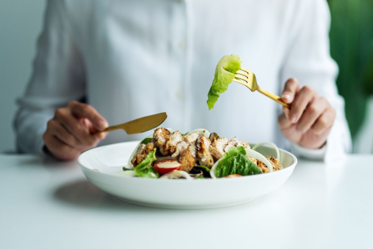 Closeup image of a woman eating chicken salad on table in the restaurant