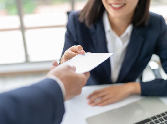 Young Asian business woman receiving salary or bonus money from boss or manager at office happily.