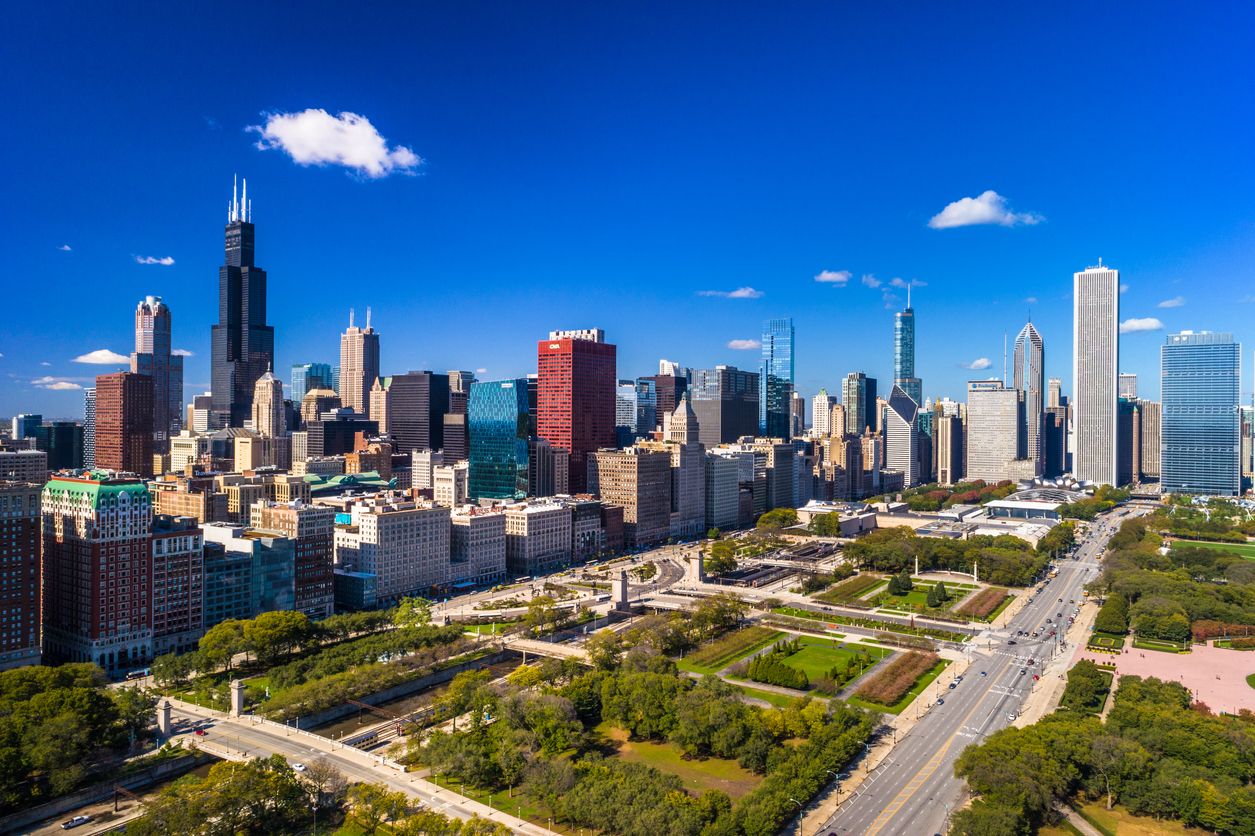Udara cakrawala pusat kota Chicago dengan langit biru tua di latar belakang dan Grand Park di latar depan.