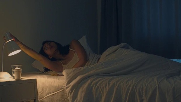 Ilustrasi perempuan hendak mematikan lampu tidur