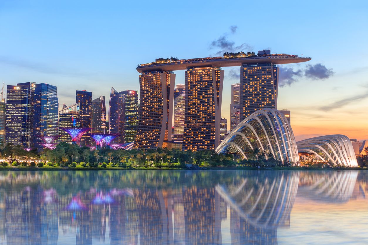 Singapore, Republic of Singapore - May 4, 2016: Supertree grove, Cloud garden greenhouse and Marina Bay Sands hotel reflecting in water at dusk with glowing lights