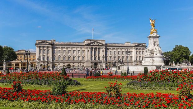 London, UK - July 18, 2015: The outside of Buckingham Palace in London during the summer showing the Main Palace, Victoria Memorial and flowers. People can be seen outside.