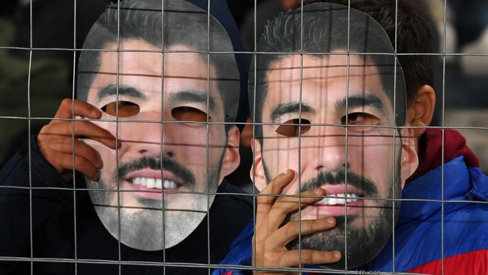 Fans of Nacional hold masks with an image of Uruguayan football star Luis Suarez during a campaign to try to convince him to return to the club, before the start of the Uruguayan First Division match between Nacional and Cerrito at the Gran Parque Central stadium in Montevideo on July 21, 2022. - A massive campaign on social networks has expanded in Uruguay so that the Uruguayan idol Luis Suárez returns to Nacional, the club of his beginnings before acquiring world fame. Under the hashtag #SuárezANacional, fans of Nacional are trying to convince him to join the club until the World Cup. (Photo by Pablo PORCIUNCULA / AFP) (Photo by PABLO PORCIUNCULA/AFP via Getty Images)