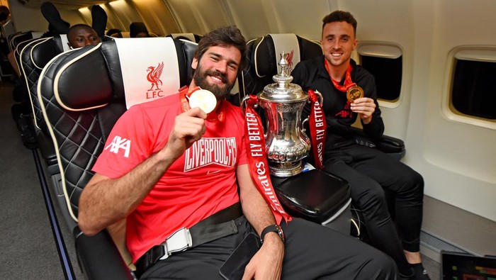 LONDON, ENGLAND - MAY 14: (THE SUN OUT, THE SUN ON SUNDAY OUT) Alisson Becker and Diogo Jota of Liverpool with the Emirates FA Cup trophy on board a flight back to Liverpool after winning the The Emirates FA Cup Final match between Chelsea and Liverpool at Wembley Stadium on May 14, 2022 in London, England. (Photo by Andrew Powell/Liverpool FC via Getty Images)