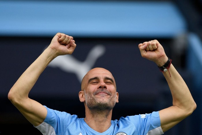 Manchester Citys Spanish manager Pep Guardiola reacts as City players celebrate on the pitch after the English Premier League football match between Manchester City and Aston Villa at the Etihad Stadium in Manchester, north west England, on May 22, 2022. - Manchester City won the Premier League for the fourth time in five seasons after a pulsating title race reached a dramatic conclusion as the champions staged an incredible comeback from two goals down to beat Aston Villa 3-2 on Sunday. - RESTRICTED TO EDITORIAL USE. No use with unauthorized audio, video, data, fixture lists, club/league logos or live services. Online in-match use limited to 120 images. An additional 40 images may be used in extra time. No video emulation. Social media in-match use limited to 120 images. An additional 40 images may be used in extra time. No use in betting publications, games or single club/league/player publications. (Photo by Oli SCARFF / AFP) / RESTRICTED TO EDITORIAL USE. No use with unauthorized audio, video, data, fixture lists, club/league logos or live services. Online in-match use limited to 120 images. An additional 40 images may be used in extra time. No video emulation. Social media in-match use limited to 120 images. An additional 40 images may be used in extra time. No use in betting publications, games or single club/league/player publications. / RESTRICTED TO EDITORIAL USE. No use with unauthorized audio, video, data, fixture lists, club/league logos or live services. Online in-match use limited to 120 images. An additional 40 images may be used in extra time. No video emulation. Social media in-match use limited to 120 images. An additional 40 images may be used in extra time. No use in betting publications, games or single club/league/player publications. (Photo by OLI SCARFF/AFP via Getty Images)