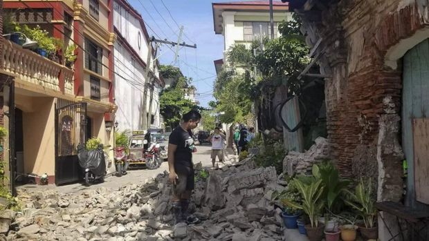 In this photo provided by the Bureau of Fire Protection, a man stands beside a damaged house after a strong earthquake struck Vigan, Ilocos Sur province, Philippines on Wednesday July 27, 2022. A strong earthquake shook the northern Philippines on Wednesday, causing some damage and prompting people to flee buildings in the capital. (Bureau of Fire Protection via AP)