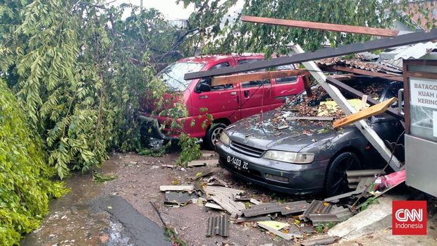 Hujan deras disertai angin kencang mengakibatkan pohon tumbang kemudian menimpa dua unit mobil di Jalan Industri, Kecamatan Cicendo, Kota Bandung, Jumat (29/7). CNN Indonesia/Huyogo Simbolon