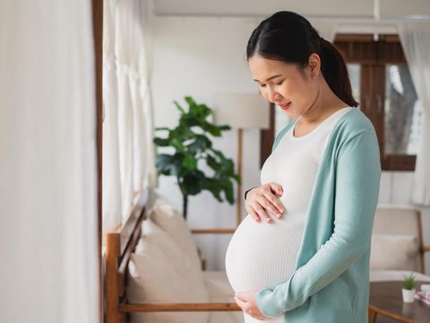 Asian young pregnant woman smile with big belly at home