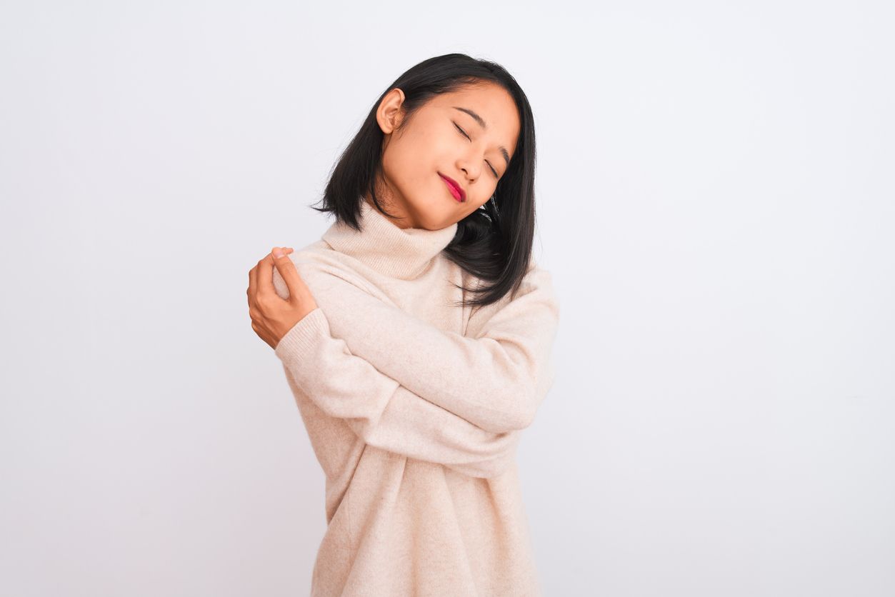Young chinese woman wearing turtleneck sweater standing over isolated white background Hugging oneself happy and positive, smiling confident. Self love and self care