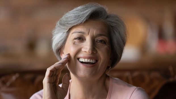Head shot portrait happy mature grey haired woman talking, looking at camera, smiling grandmother making video call to relatives, chatting online, speaking to webcam, blogger recording vlog