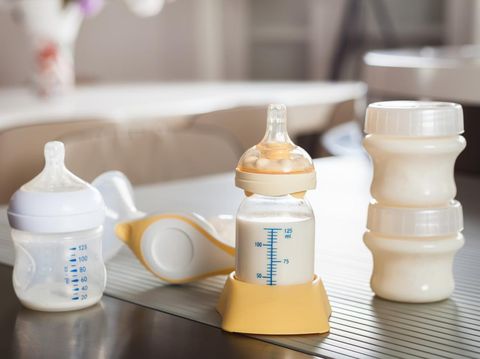 Baby bottle with milk and manual breast pump. A lot of full bottles with breast milk on the background. Mother's milk - the most healthy food for newborn