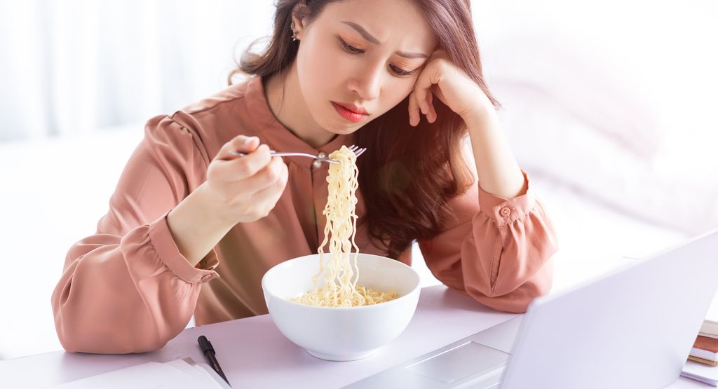 Asian businesswoman has to eat noodles while working