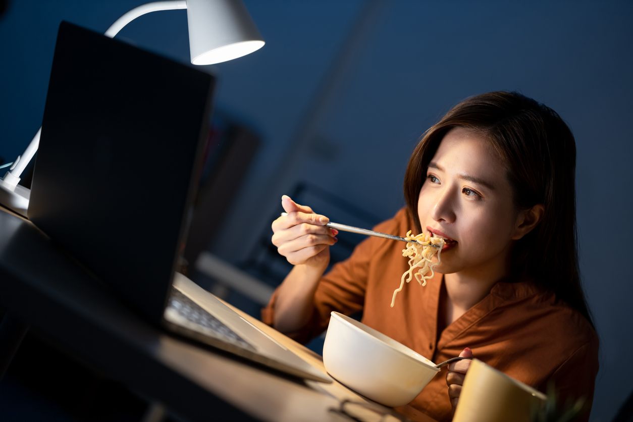 Ilustrasi wanita makan mi instan depan laptop