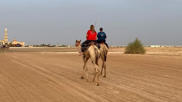 Camel trainer Jana Schmiedel and Michelle O'Malley ride camels during a training session at the Arabian Desert Camel Riding center in Dubai, United Arab Emirates August 1, 2022. REUTERS/Abir Al Ahma