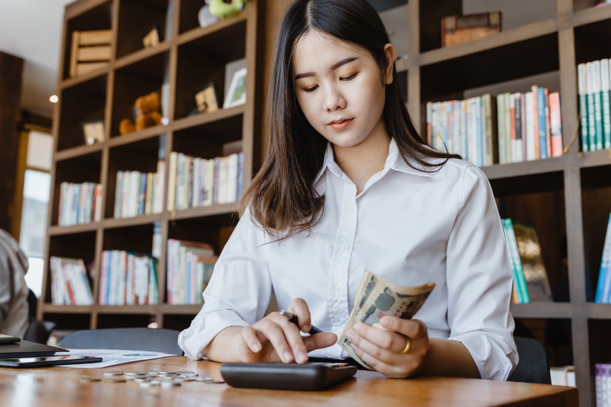 Asian girl using calculator for personal accounting and hold Japanese Yen