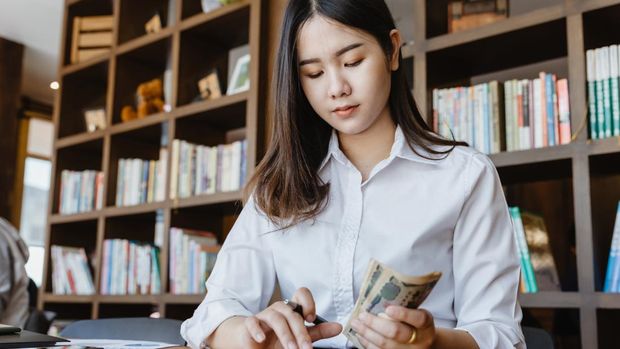 Asian girl using calculator for personal accounting and hold Japanese Yen