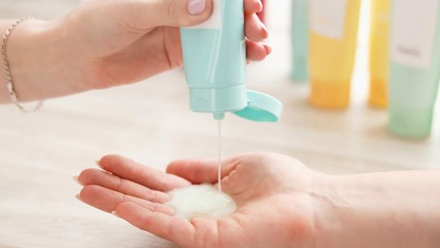 Women's hands applying cleansing lotion with to cleanse the skinhygiene tubes on white background, natural light. Hygienic concept.