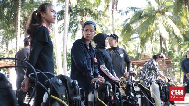 Sekelompok Mahasiswa dari sembilan perguruan tinggi di Indonesia bersama masyarakat pulau yang berada di Dusun Jelarangan Pahawang, Kabupaten Pesawaran, Lampung secara hikmat mengikuti upacara pengibaran bendera HUT Kemerdekaan RI ke-77 tahun dari dasar laut, Rabu (17/8/2022). (CNNIndonesia/Zainal)