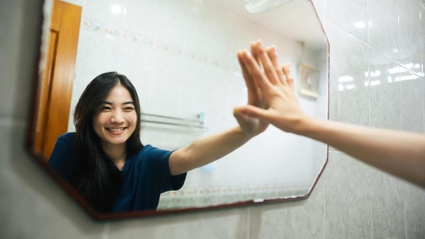 1276364966 Young adult smile asian woman practice self talk conversation in the morning in bathroom at home. Hand hi-touch at mirror. Healthy lifestyle after wake up concept.
