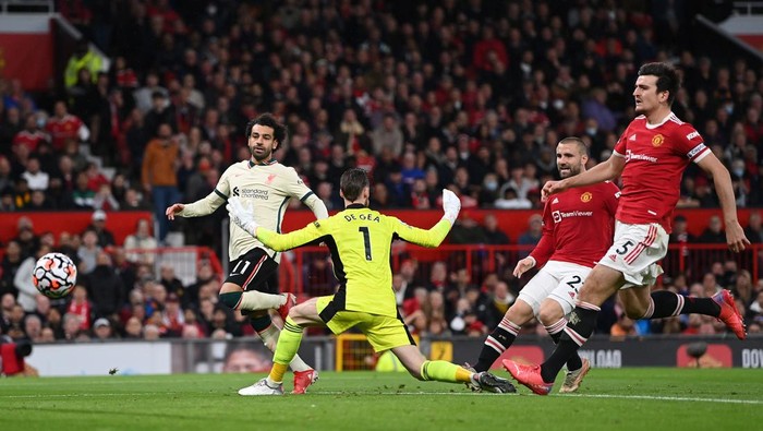 MANCHESTER, ENGLAND - OCTOBER 24:  Mohamed Salah of Liverpool shoots past Manchester United goalkeeper David De Gea to score his hat trick as Harry Maguire and Luke Shaw look on during the Premier League match between Manchester United and Liverpool at Old Trafford on October 24, 2021 in Manchester, England. (Photo by Shaun Botterill/Getty Images)