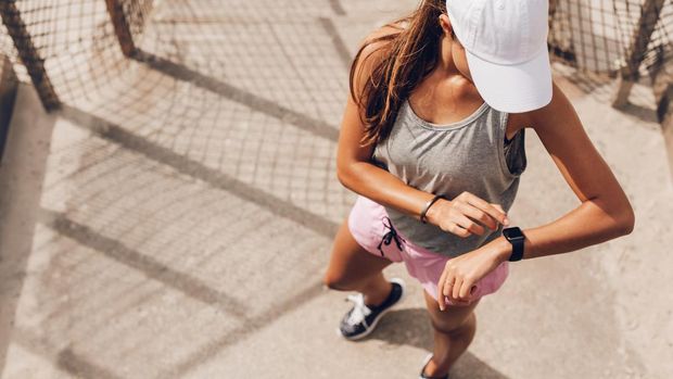 Young woman checking progress on smart watch. Female runner looking at smart watch heart rate monitor.