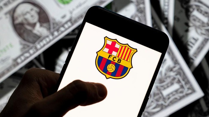 CHINA - 2021/04/23: In this photo illustration the Spanish professional football team the Futbol Club Barcelona logo seen displayed on a smartphone with USD (United States dollar) currency in the background. (Photo Illustration by Budrul Chukrut/SOPA Images/LightRocket via Getty Images)