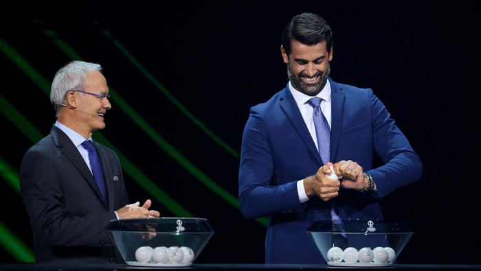 ISTANBUL, TURKEY - AUGUST 26: Special guest, Volkan Demirel is handed opens a draw ball as UEFA Deputy General Secretary, Giorgio Marchetti looks on during the UEFA Europa Conference League 2022/23 Group Stage Draw on August 26, 2022 in Istanbul, Turkey. (Photo by Lukas Schulze - UEFA/UEFA via Getty Images)