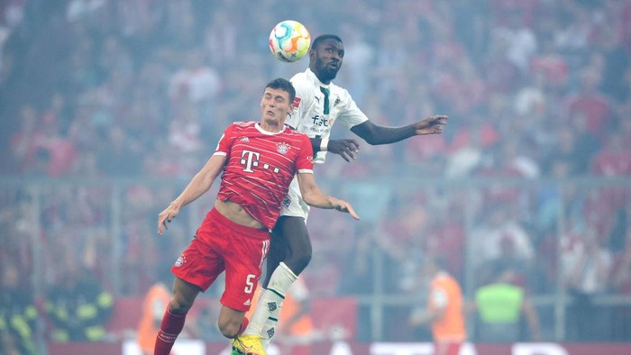 MUNICH, GERMANY - AUGUST 27: Benjamin Pavard of Bayern Munich jumps for the ball with Marcus Thuram of Borussia Monchengladbach during the Bundesliga match between FC Bayern München and Borussia Mönchengladbach at Allianz Arena on August 27, 2022 in Munich, Germany. (Photo by Alexander Hassenstein/Getty Images)