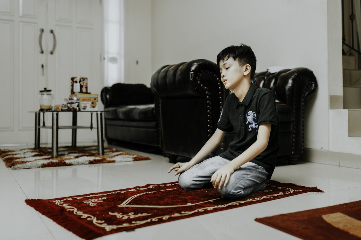 asian muslim kid is salah (doa) in home
