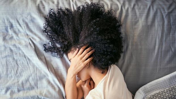 ilustrasi sakit telinga Shot of a young woman suffering from depression in her bedroom