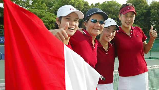 Indonesian tennis player Angelique Widjaja (R) gives the thumbs-up with her teammate Wynne Prakusya (2nd R), Sandy Gumulya (L) and team captain (2nd L) in front of a national flag just after their victory against China during the Fed Cup Asia/Oceania qualifying Group 1 tournament 26 April 2003. Indonesian defeated China 2-1 to advance to the play-off for the Fed Cup World Group in July.     AFP PHOTO/Toru YAMANAKA (Photo by TORU YAMANAKA / AFP)