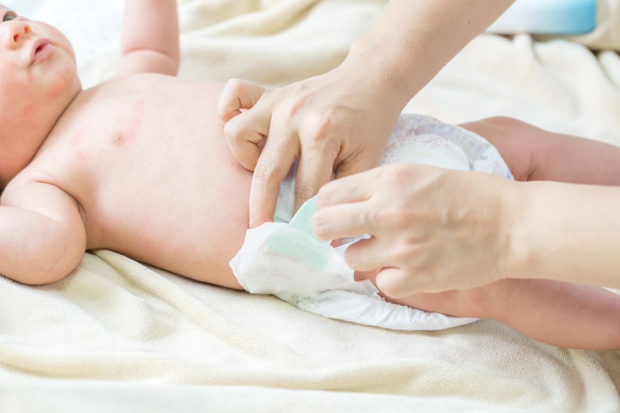 Mother putting diaper on her baby