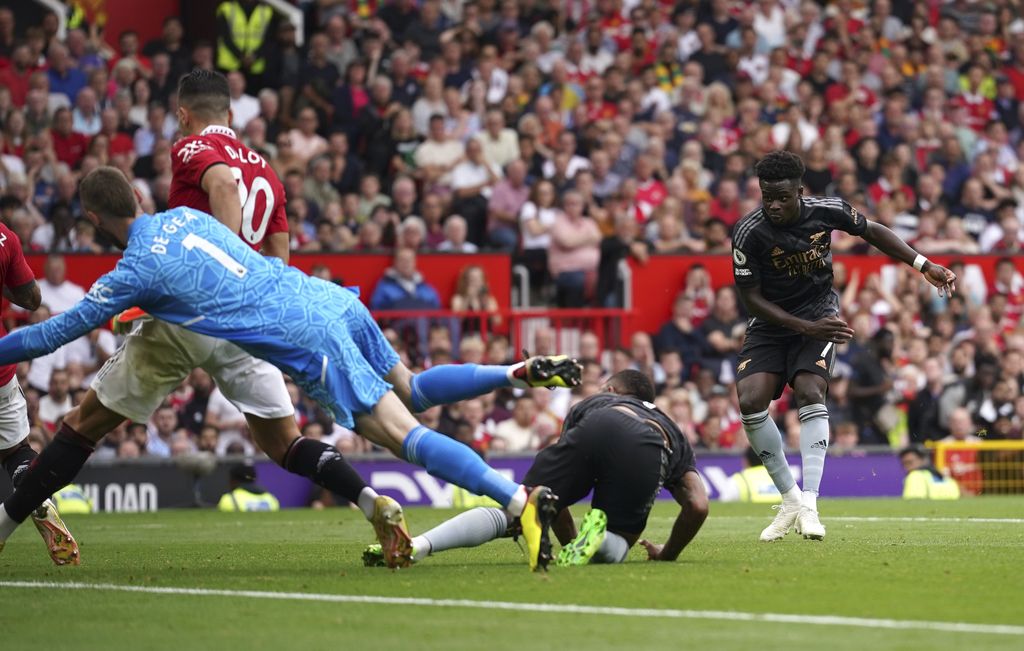 Arsenal's Bukayo Saka, right, scores his side's opening goal during the English Premier League soccer match between Manchester United and Arsenal at Old Trafford stadium, in Manchester, England, Sunday, Sept. 4, 2022. (AP Photo/Dave Thompson)