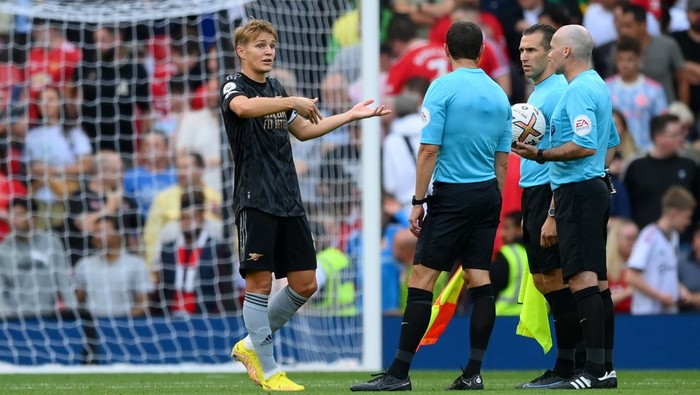 MANCHESTER, ENGLAND - SEPTEMBER 04: Martin Oedegaard of Arsenal interacts with match referee Paul Tierney and match officials during the Premier League match between Manchester United and Arsenal FC at Old Trafford on September 04, 2022 in Manchester, England. (Photo by Shaun Botterill/Getty Images)