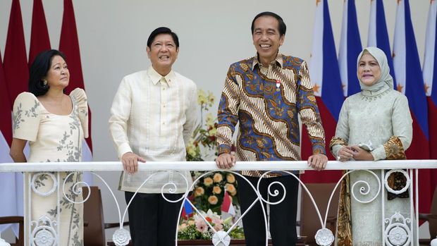 Philippine President Ferdinand Marcos Jr.  center left, and his wife Madame Louise Araneta Marcos, left, give light to Indonesian President Joko Widodo, center right, and his wife Iriana during their meeting at the presidential palace in Bogor, Indonesia, Monday, September , 5, 2022. (AP Photo/Achmad Ibrahim, Pool)